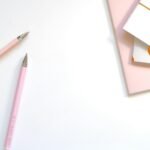 A minimalist flat lay of pink pens and pastel notebooks on a smooth white background, ideal for office and school themes.