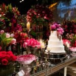 Luxurious wedding reception setup featuring a white layer cake amidst vibrant floral arrangements.