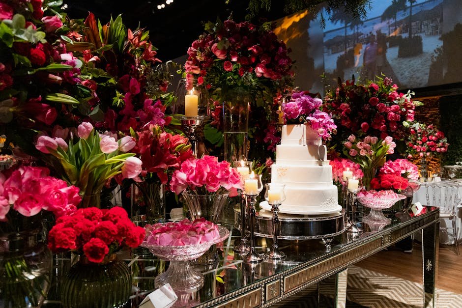 Luxurious wedding reception setup featuring a white layer cake amidst vibrant floral arrangements.